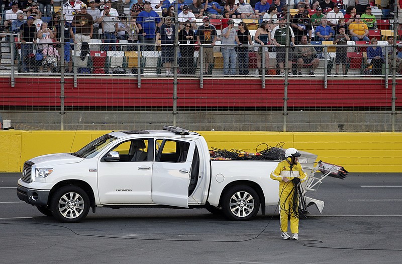 A worker cleans up a broken television camera cable that damaged several cars Sunday night during the Coca-Cola 600 at Charlotte Motor Speedway in Concord, N.C..