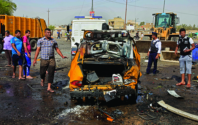 Iraqis inspect the scene of a bomb attack Tuesday at Sadr City in Baghdad, Iraq. A bomb left on a Baghdad minibus and a suicide truck bomb north of the Iraqi capital killed and wounded dozens of people, officials said. The attacks followed a particularly bloody day that left scores dead.