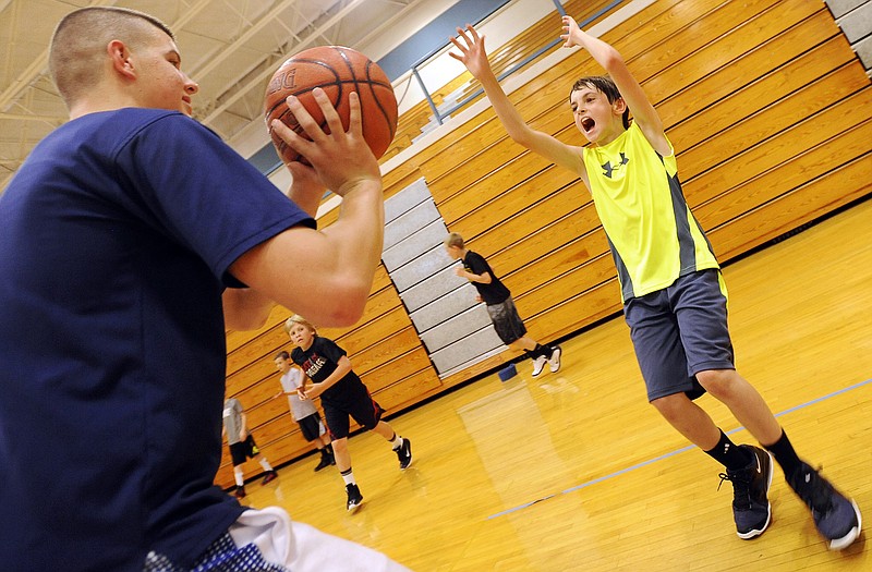 Joey DeFeo shouts out as he steps up to cut off the shot of Helias' Trevor Koelling at the defensive skills station Wednesday in the Helias boys basketball summer camp at Rackers Fieldhouse.