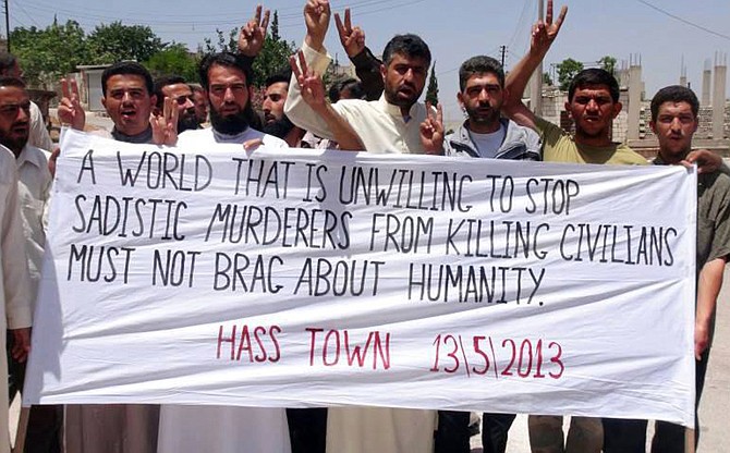 Anti-Syrian regime protesters hold a banner Friday during a demonstration in Hass town, Idlib province, northern Syria. Syrian troops on Friday attacked a convoy trying to evacuate the wounded from a central town near the border with Lebanon, killing many people, as rebel reinforcements infiltrated the besieged area to fight government forces backed by Lebanese Hezbollah fighters, activists said.