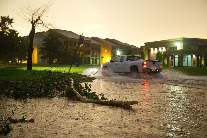 A pickup truck drives through flooded Highline Blvd. Friday where several trees were also down after a tornado on the ground near El Reno, Okla., just south of Interstate 40.