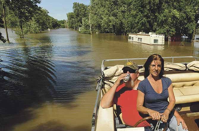 Osage City, Mo., residents Dave Kempker and Doris Panaitz cruise slowly past a number of properties and vehicles overrun by flood waters along Engineers Road on the banks of the Osage River after traveling downstream to check on the home of Panaitz's fiancee Jim Schaller on Saturday afternoon.