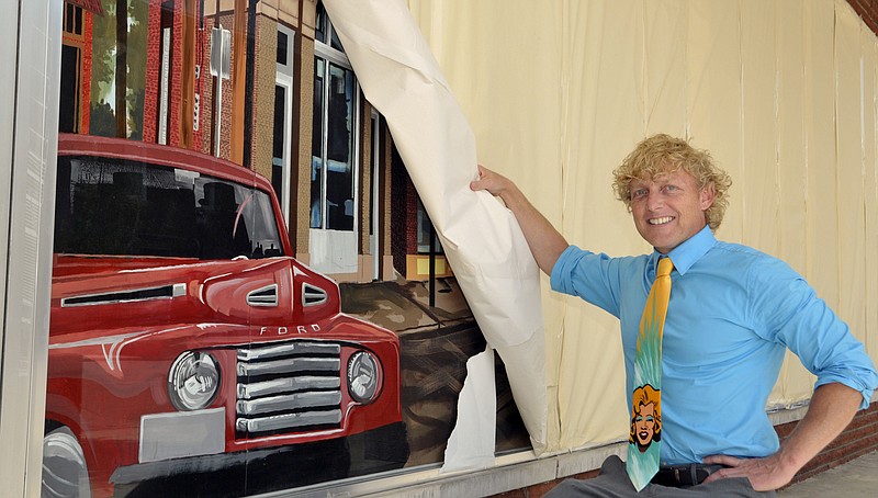 Artist Jim Dyke peels back the covering to reveal a portion of the mural he's painted to reflect historic Jefferson City.