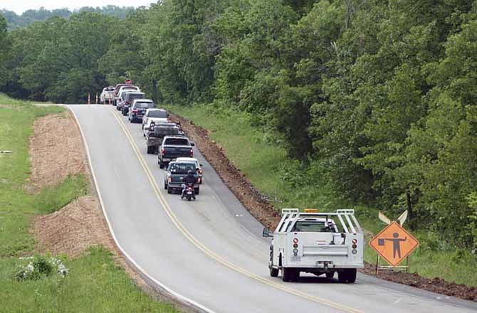 A long line of vehicles awaits a flagman directing traffic around a construction site on Missouri Highway 42 near Lake of the Ozarks State Park. 