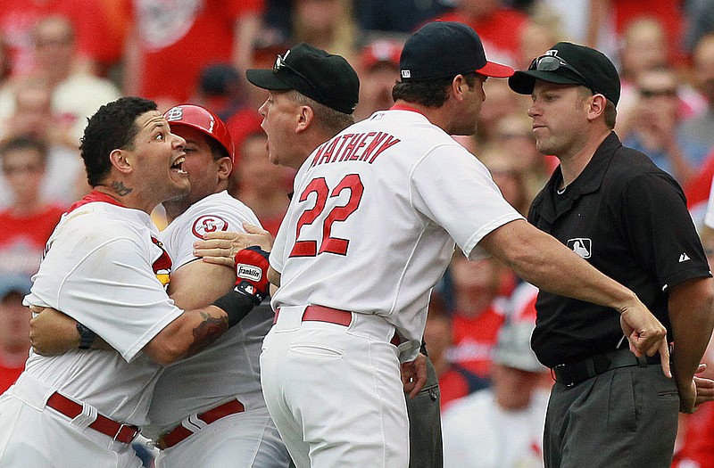 Yadier Molina (left) is restrained by his brother, Cardinals first base coach Bengie Molina, as he protests his ejection by first-base umpire Clint Fagan (far right) in the third inning of Sunday's game against the Giants at Busch Stadium. Cardinals manager Mike Matheny also argues with Fagan and was likewise ejected from the game as umpire Mike Everitt (center) tries to calm matters.