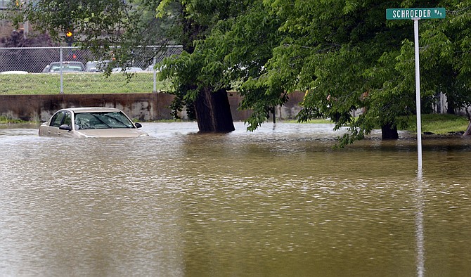 An abandoned vehicle sits in flood waters Saturday that are covering the street near the intersection of Schroeder Way and Walnut Street.