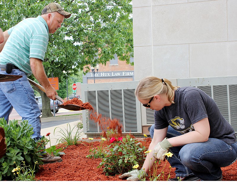 Callaway County Presiding Commissioner Gary Jungermann spreads mulch while Sarah Gladman of Callaway County Collector Pam Oestreich's office plants flowers Wednesday morning on the south side of the courthouse.