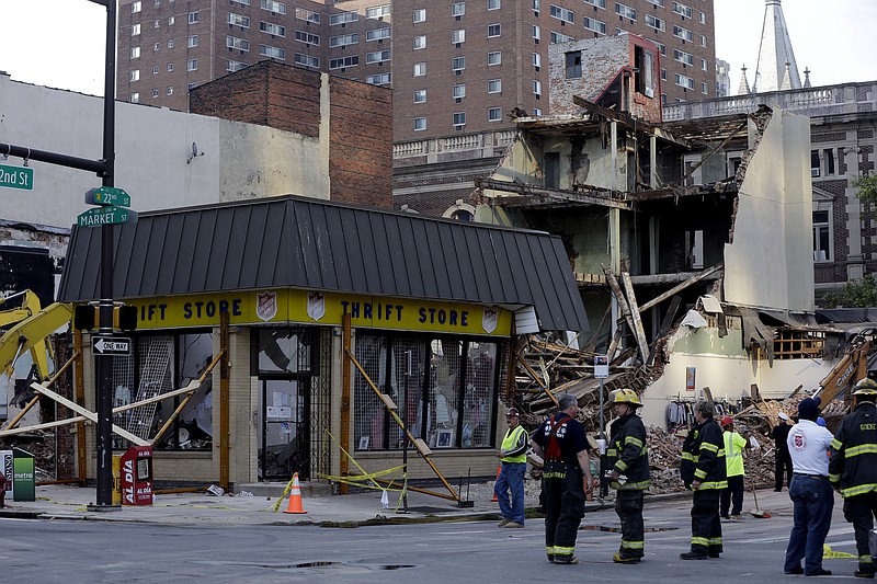 Firefighters stand near the aftermath of a building collapse in Philadelphia. On Wednesday, the building under demolition collapsed onto a neighboring thrift store, killing six people and injuring 13, including one who was pulled from the debris nearly 13 hours later.