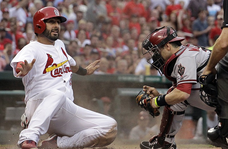 Daniel Descalso of the Cardinals is safe at home, sliding in before the tag of Diamondbacks catcher Miguel Montero, during the fourth inning of Thursday night's game at Busch Stadium.