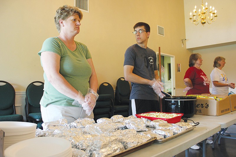 Julie Murphy and Nick Russell of Southside Baptist Church prepare to hand out burgers and dogs at the Fulton Soup Kitchen Thursday. About 200 volunteers like them gave out more than 13,000 meals in 2012, up exponentially from just two years before.