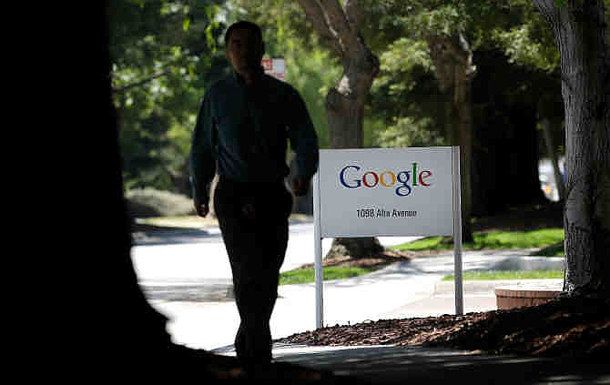 A man walks past a Google sign in Mountain View, Calif., Friday, June 7, 2013. Google CEO Larry Page is denying reports linking the Internet search company to a secret government program that has provided the National Security Agency access to email and other personal information transmitted on various online services. 