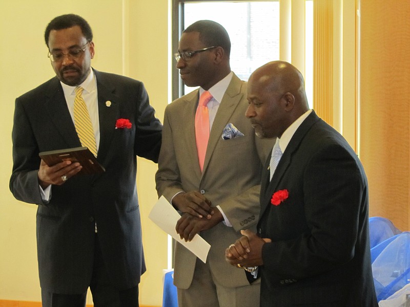 W. T. Edmonson, left, presents the 2013 Father of the Year award to Rev. Lard Andrews, right, as Justin Andrews, middle, listens at the Juneteenth banquet. Justin Andrews nominated his father for the award, calling him a "divine standard" for fathers. 