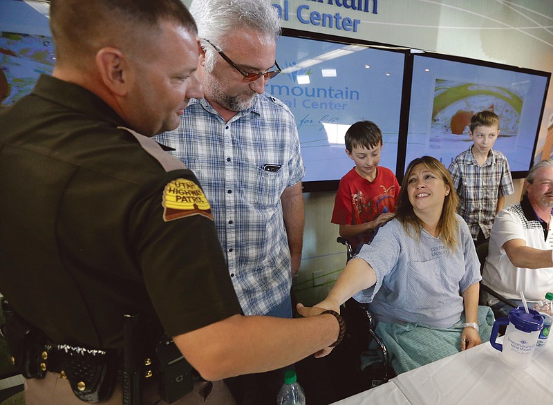 Lynette Hales shakes hands with Utah Trooper Cameron Fawson while Jim Gerber, center, watches at Intermountain Medical Center in Murray, Utah. Hales was nearly 100 miles from Salt Lake City on a rural stretch of highway surrounded by nothing but barren salt flats when her twin unborn babies decided it was time. She called police for help, but the nearest highway troopers were about 30 miles east on Interstate 80. The first baby couldn't wait. She delivered him at about 9 a.m. Sunday from the passenger seat of a minivan with the help of a friend who was driving her back from an overnight outing in Wendover. Her twin boys, J.J. and A.J., were born in a minivan with the help of Gerber and Fawson along with two other law enforcement officers. 