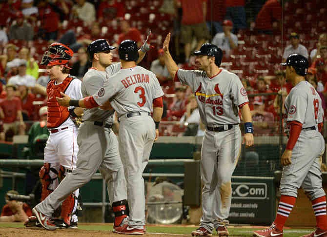 Matt Holliday, second from left, is congratulated at home plate after his 10th inning grand slam in a game where the St. Louis Cardinals beat the Cincinnati Reds 11-4 in 10 innings, Sunday, June 9, 2013, at Great American Ball Park in Cincinnati. 