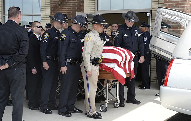 The body of fallen Bardstown police officer Jason Ellis, who was killed in an ambush slaying on May 25, is placed in a hearse during his funeral at the Parkway Baptist Church in Bardstown, Ky. The Bardstown Police Department has received threats that more officers will be targeted, prompting an investigation by the FBI and state police.