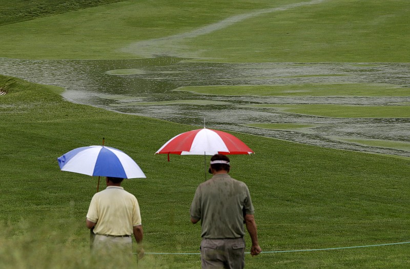 Golf fans walk along the 16th fairway as rain falls earlier this week at Merion Country Club in Ardmore, Pa. It could be a wet start to the tournament.