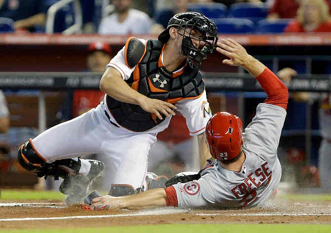 St. Louis Cardinals' David Freese, right, slides safely into home plate as Miami Marlins catcher Rob Brantly attempts the tag during the first inning of a baseball game on Saturday, June 15, 2013, in Miami. 
