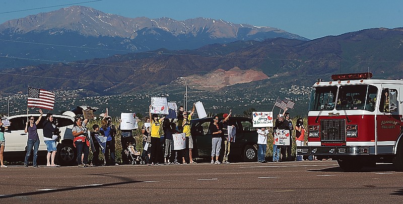 People line Old Ranch Road on Sunday morning to cheer for the firefighters returning from a shift of fighting the Black Forest Fire outside the fire camp at Pine Creek High School in Colorado Springs, Colo. The scars of last summer's Waldo Canyon Fire can be seen in the background.
