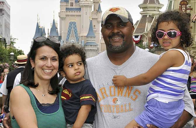 This June 2013 photo provided by Disney PhotoPass Service shows Creed Anthony of Indianapolis with his daughter Sophie, 5, son Isaac, 2, and wife Amal, on a visit to Disney World's Magic Kingdom in Lake Buena Vista, Fla. Anthony is an example of a new generation of hands-on dads who don't just change the occasional diaper but who view "parenting as a partnership," as he put it, by being as involved in childrearing as moms.