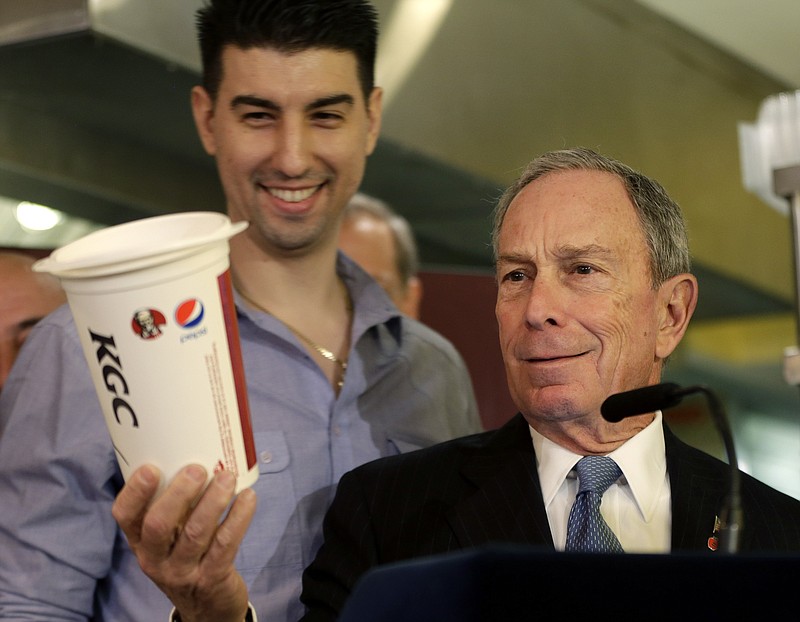 New York City Mayor Michael Bloomberg looks at a 64-ounce cup March 12, as Lucky's Cafe owner Greg Anagnostopoulos, left, stands behind him, during a news conference at the cafe in New York. In a letter to congressional leaders Tuesday, the mayors of New York, Los Angeles, Chicago and 15 other cities say it's "time to test and evaluate approaches limiting" the use of the subsidies' for sugar-laden beverages.