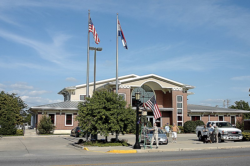 Allan Burger, on the ladder in the center, places a flag in one of the brackets mounted on the period streetlights in front of the California City Hall to complete his Eagle Scout project. The flags are to be on display 24 hours a day on the selected poles at the city hall and county courthouse.