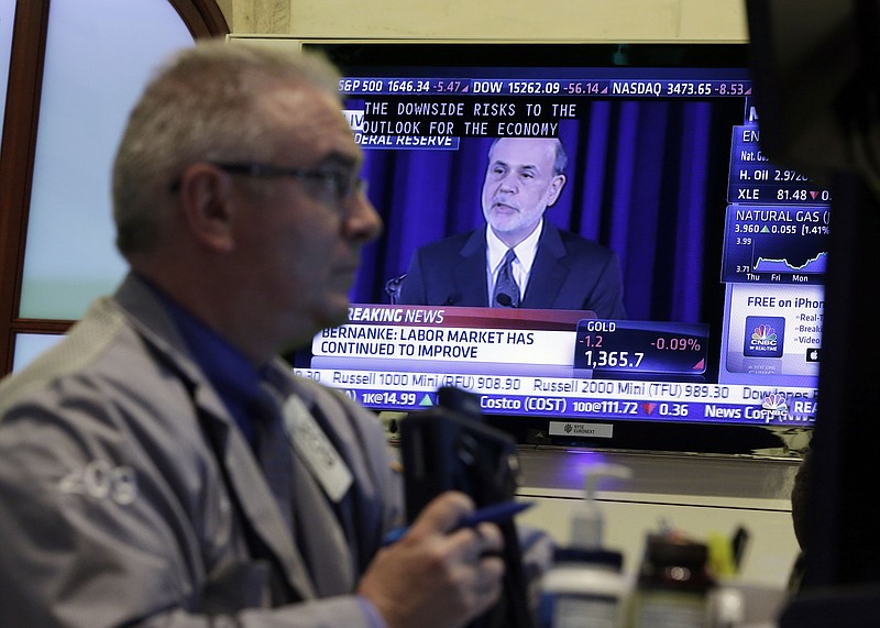 Fed Chairman Ben Bernanke is on a television screen as trader James Dresch works in a booth on the floor of the New York Stock Exchange Wednesday, June 19, 2013.  The Federal Reserve offered a hint Wednesday that it's moving closer to slowing its bond-buying program, which is intended to keep long-term interest rates at record lows.