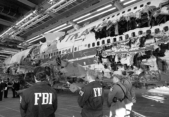 In this Nov. 19, 1997 photo, FBI agents and New York state police guard the reconstruction of TWA Flight 800 in Calverton, N.Y. The jetliner exploded and crashed July 17, 1996 while flying from New York to Paris, killing all 230 people aboard. 