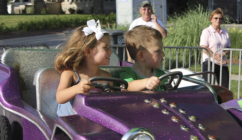 Ava Smith, 3, and Brock Smith, 2, of Fulton take a spint on a ride at the carnival Thursday as their grandparents, Larry and Linda Smith, watch in downtown Fulton. The carnival opened Thursday evening - preceding the Fulton Street Fair which runs today and tomorrow on and around the square downtown. 
