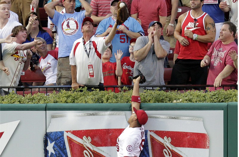 Cardinals center fielder Jon Jay leaps at the wall as a fan catches a home run ball hit by Wellington Castillo of the Cubs in the third inning of Thursday night's game at Busch Stadium.