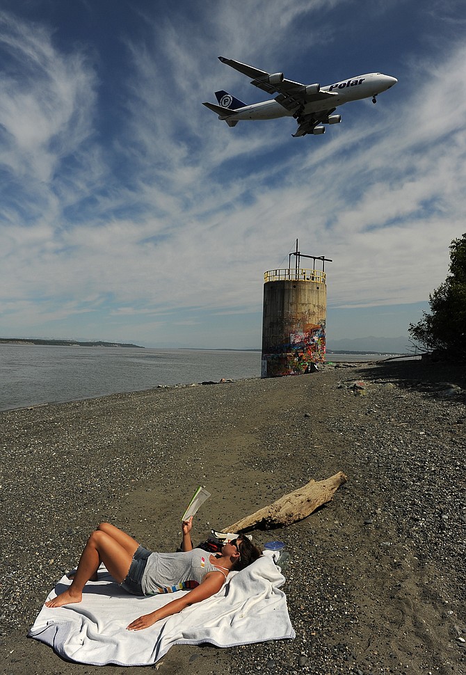 Liz Gobeski soaks up the sun on the beach Tuesday at Point Woronzof as a Polar Air Cargo jet comes in for a landing at Ted Stevens Anchorage International Airport as the temperature reached into the 80's in Anchorage, Alaska.