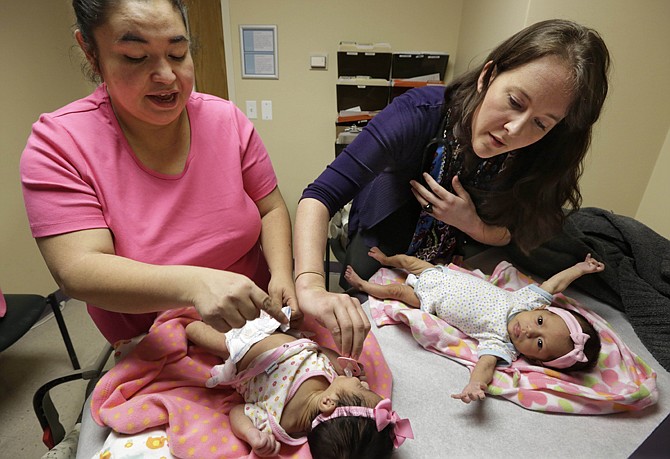 Medical resident Stephanie Place, right, examines 2-month-old twins Abigale, left, and Valeria Lopez as their mother, Carolina Lopez helps at the Erie Family Health Center in Chicago. As clinics gear up for the expansion of health insurance, they're recruiting young doctors. Heavy recruitment means Place will have no trouble fulfilling her dream. She'll also be able to pay off $160,000 in student loans through a federal program aimed at encouraging doctors to work in areas with physician shortages.