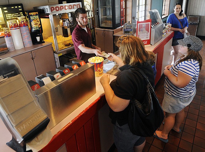 Truman 4 Theaters employee Kyle Pickett serves up refreshments as moviegoers hit the concessions to stock up on popcorn and soda before the early matinee showing of "Epic" on Saturday afternoon.