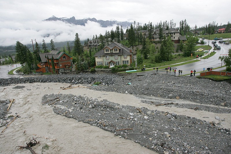 Residents in the Eagle Terrace neighborhood of Canmore, Alberta, look out over what was the only road into the area on Friday, after Cougar Creek flooded.