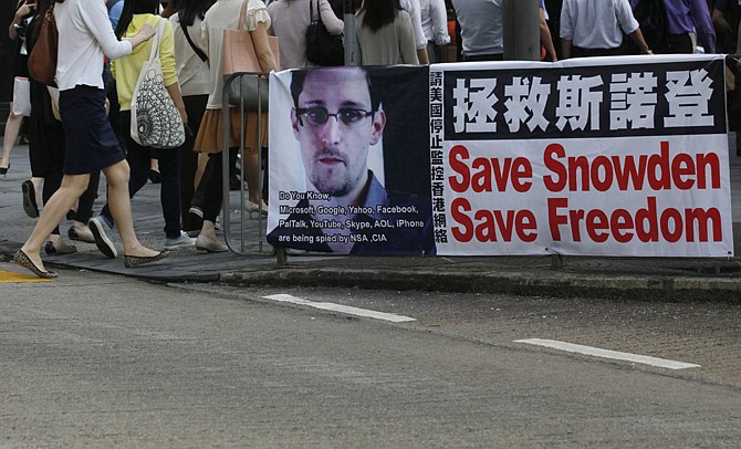 A banner supporting Edward Snowden, a former CIA employee who leaked top-secret documents about sweeping U.S. surveillance programs, is displayed Monday at Central, Hong Kong's business district. Top officials from the Obama and Bush administrations say the government's newly exposed secret surveillance programs have been essential to disrupting terrorist plots and have not infringed on Americans' civil liberties.