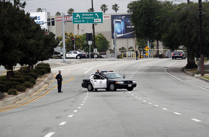 Los Angeles police officers close off a city street Tuesday after two police officers were shot and wounded in an attack outside a police station in the Mid-City area of Los Angeles. A gunman ambushed two detectives returning to a police station, but they received only minor injuries.