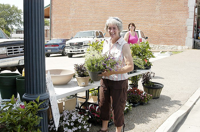 Alice Longfellow shows off one of the plants among the many available at the Longfellow Garden Center booth at the Taste of Local Missouri event Saturday, June 22, in downtown California.