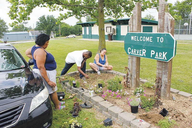  From left: Mary Galbreath, Stacy Childs and Lisa Thompson plant flowers to beautify the Carver Park sign Wednesday. The residents began working on the sign when they noticed weeds had grown so tall they were obscuring part of the park's name.