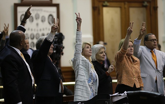 Sen. Wendy Davis, D-Fort Worth, center, who tries to filibuster an abortion bill, holds up a no vote as time expires, Wednesday in Austin, Texas. Amid the deafening roar of abortion rights supporters, Texas Republicans huddled around the Senate podium to pass new abortion restrictions, but whether the vote was cast before or after midnight is in dispute.