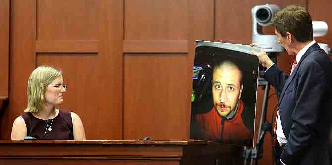 Mark O'Mara, George Zimmerman's attorney, displays a photo of Zimmerman taken the night of the shooting of Trayvon Martin, to Zimmerman's physician, Lindzee Folgate, during her testimony on the 15th day of Zimmerman's trial in Seminole circuit court, in Sanford, Fla., Friday, June 28, 2013. Zimmerman has been charged with second-degree murder for the 2012 shooting death of Trayvon Martin.