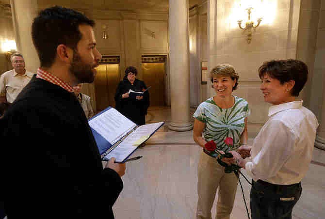 Marriage commissioner Jared Scherer, left, officiates as Pam Shaheen, center, marries Mary Beth Gabriel at City Hall in San Francisco, Friday, June 28, 2013.