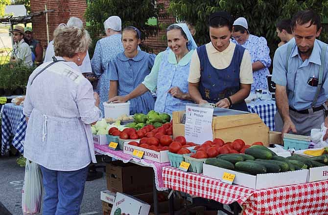 
Alma Stauffer talks with a customer at her family's produce stand at Friday's farmers market in Versailles. Pictured, from left to right, are Susie, Alma, Katie and Leon Stauffer. The Stauffers have participated in Versailles' previous farmers market before. "This is just a small portion of what we grow," Leon said.