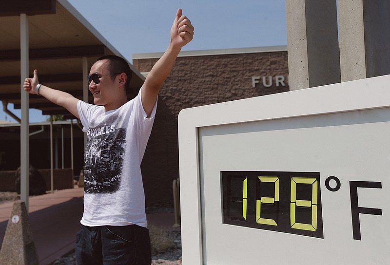Cheng Jia, of China, poses by a digital thermometer at the Furnace Creek Vistitor Center in California's Death Valley National Park. Excessive heat warnings will continue for much of the Desert Southwest as building high pressure triggers major warming in eastern California, Nevada, and Arizona. 