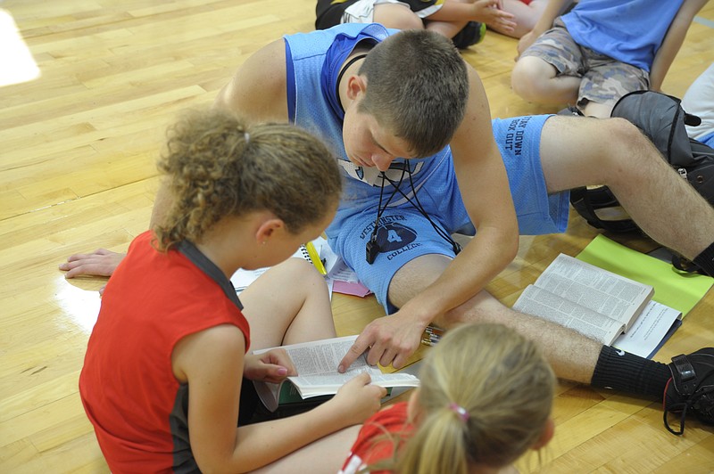 After more than an hour of basketball skills training, Sports Crusader campers settle in for Half-Time, with scripture reading and discussion. The college athletes like Nathaniel Caudel, California, who coach the sports camp also lead the devotional, developing relationships with the campers, like Paige Randolph. Democrat staff/Michelle Brooks