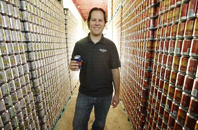 In this Monday, June 3, 2013 photo, Brewmaster Brian O'Reilly holds a can of Helles Golden Lager with a 360 Lid as he poses for a portrait at the Sly Fox Brewing Company, in Pottstown, Pa. Brewers and consumers debate using bottles or cans, innovation of the age-old staple continues as breweries seek to differentiate themselves on expanding beer shelves. Budweiser is selling a bowtie-shaped can that mirrors its iconic logo, Miller Lite is sold in a punch-top can, Sam Adams Boston Lager comes in cans designed to improve taste and now Sly Fox Brewing Co. is selling beer in "topless" cans with a peel-back lid that essentially turns it into a glass. 