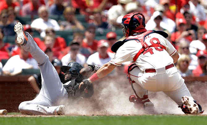 Miami Marlins' Adeiny Hechavarria, left, is tagged out at home by St. Louis Cardinals catcher Tony Cruz during the fourth inning of a baseball game on Saturday, July 6, 2013, in St. Louis. 