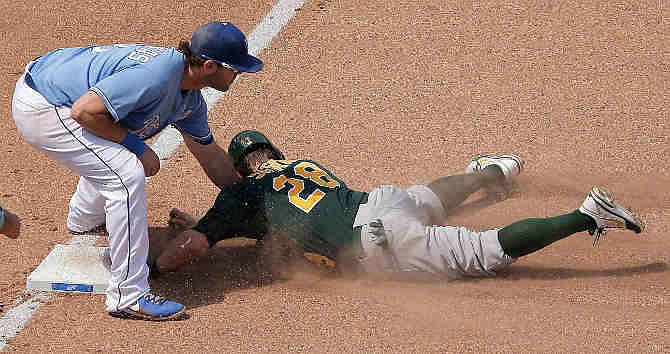 Oakland Athletics' Eric Sogard is tagged out at third by Kansas City Royals third baseman Mike Moustakas as he tired to advance on a fly ball hit by Coco Crisp during the seventh inning of a baseball game Saturday, July 6, 2013, in Kansas City, Mo. Sogard was out at third for the second out of the double play.