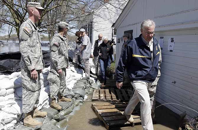 In this April 20, 2013 file photo, Gov. Jay Nixon, right, steps over a puddle after meeting with members of the Missouri National Guard as they made spring flood preparations in Clarksville. More than 1,300 Missouri National Guard employees will be losing some work days in the next three months, thanks to the federal government's budget sequester.
