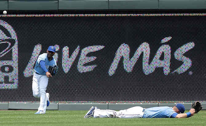 Kansas City Royals center fielder Jarrod Dyson, left, throws the ball after left fielder Alex Gordon, right, dove for it but missed an RBI-double hit by Oakland Athletics' Eric Sogard during the second inning a baseball game on Sunday, July 7, 2013, in Kansas City, Mo. 