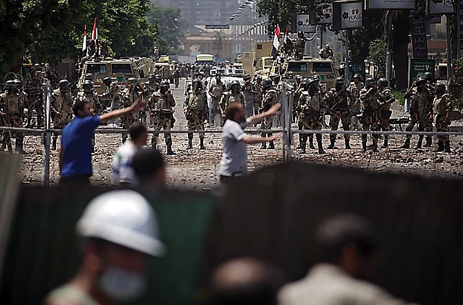 Supporters of ousted President Mohammed Morsi take cover as Egyptian army stand guard around the Republican Guard building in a suburb of Cairo. Egyptian soldiers and police opened fire on supporters of the ousted Islamist hardliner early Monday in violence that left dozens of people dead.
