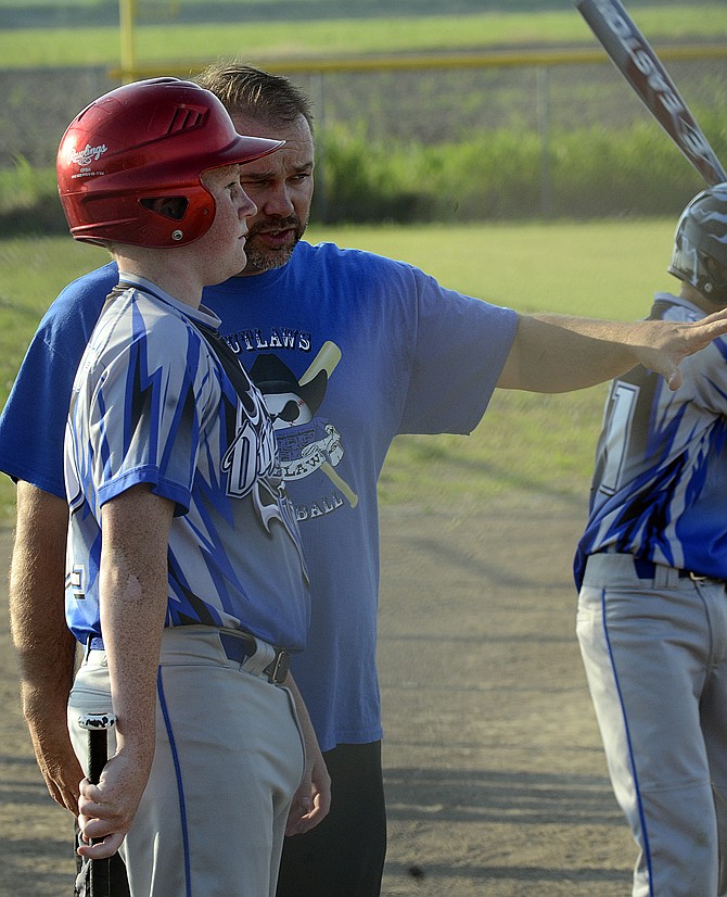 Russellville coach and volunteer Michael Miller talks with a player prior to his turn at bat in the team's game against Wardsville. Miller, along with a few other parents, pioneered the community youth baseball program, Outlaw Baseball, in order to give their children more opportunity to get on the field. 
